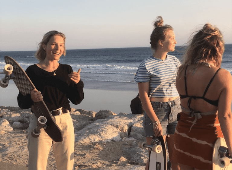 girls surfskating in front of the ocean