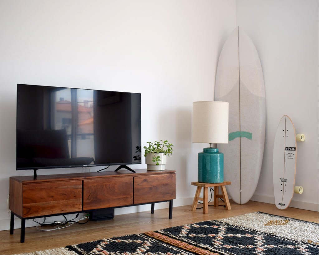 livingroom, tv on a wooden cupboard, lamp, surfboard